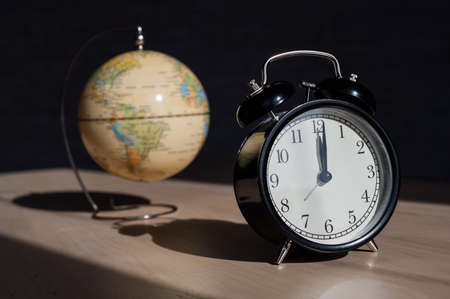 Alarm clock and globe on a wooden table. Its time to travel. World time.のeditorial素材