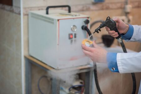 A dental technician makes partial dentures on a mechanized machine. The production of the false jaw...