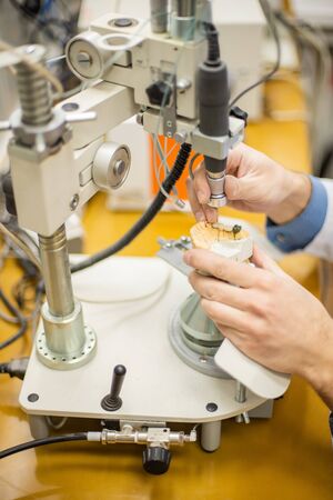 A dental technician makes partial dentures on a mechanized machine. The production of the false jaw...