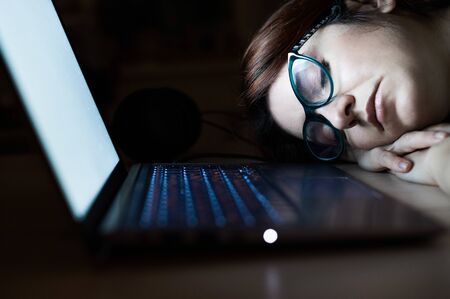 The exhausted employee worked overtime and fell asleep at his desk. Deadline Work at night with a...