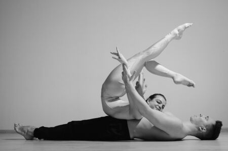 Heavy circus pose. A young man holds a flexible woman. Two acrobats or ballet dancers posing on a white background. A pair of gymnasts perform art.の写真素材