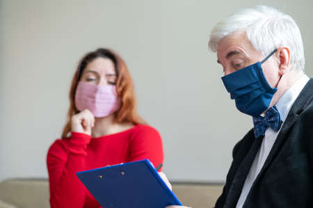 Male psychotherapist advises a female client in a medical mask. Moral support during the coronavirus...