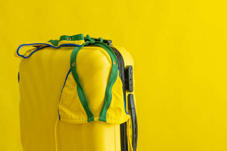 Female bikini on a suitcase on a yellow background. Set for summer holidays at sea. Composition of a...