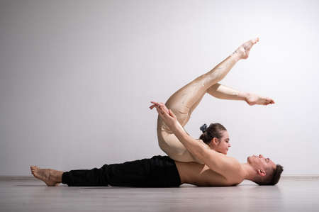 Acrobatic couple perform number on a white background. A duet of gymnasts rehearsing a performance with support. A man and a very flexible woman are dancing.の写真素材
