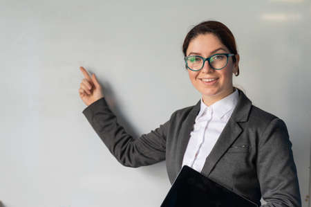 Beautiful red-haired woman in a suit with a digital tablet in her hands. A smiling female teacher...