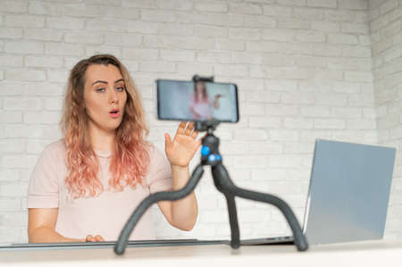 A woman sings and plays an electronic piano and conducts a video blog on a smartphone. A girl takes...