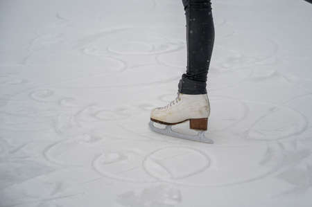 Figure skating on the street at an outdoor ice rink. Close-up of the skaters legs on ice. A woman...