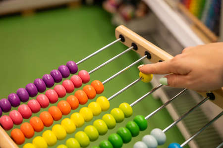 Closeup female hand calculating with balls on wooden rainbow abacus for number calculation. The concept of learning arithmetic for preschoolers.の写真素材