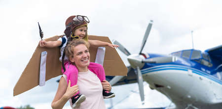 A loving Caucasian woman is playing with her little daughter in airplanes at the airfield. A little...