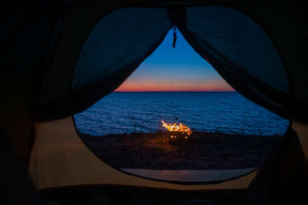 View from a tourist tent on bonfire on the seashore at sunset.の写真素材