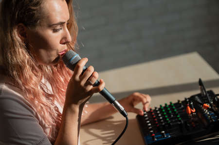 A woman sings a song into a microphone and records her singing.