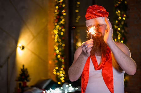 Santa with christmas sparkles. A man with a red beard in a hat of Santa Claus and a T-shirt for an...