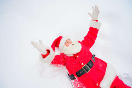 Happy santa claus lying in the snow and fooling aroundの写真素材