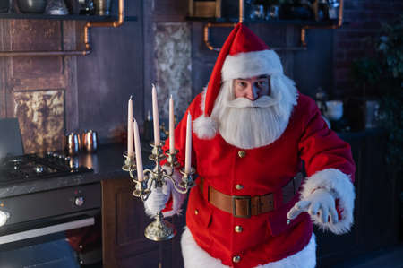 Santa claus sneaks up at night and holding a candelabrum.の写真素材