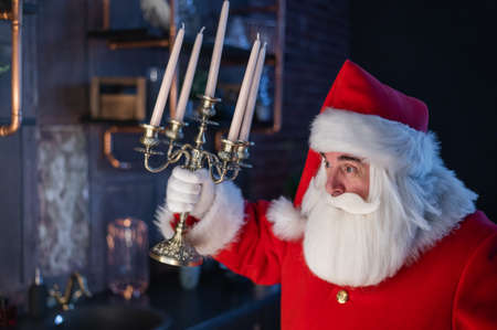 Santa claus sneaks up at night and holding a candelabrum.の写真素材