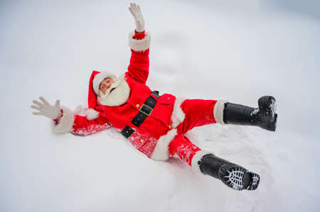 Happy santa claus lying in the snow and fooling aroundの写真素材