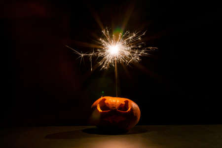 Halloween pumpkin with scary carved grimace and sparklers.の写真素材