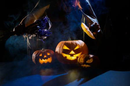 Witch casts a spell on a steaming pumpkin in the dark on Halloweenの写真素材