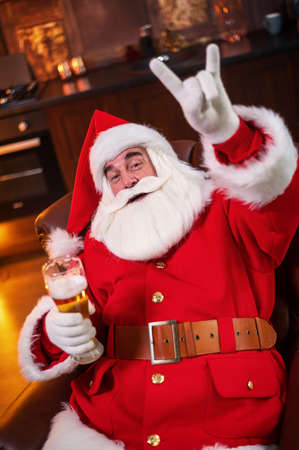 Santa Claus drinks beer while sitting in a leather armchairの写真素材
