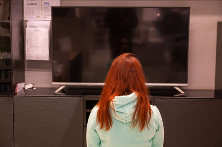 26 february 2020, Russia, Novosibirsk: A red-haired woman chooses a TV in IKEAのeditorial素材