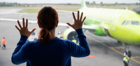 The woman leaned at the window at the airport