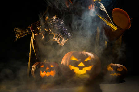 Witch casts a spell on a steaming pumpkin in the dark on Halloween