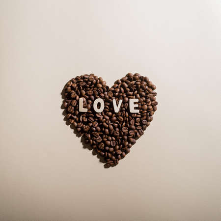 Coffee beans in the shape of a heart and the inscription love on a backgroundの写真素材