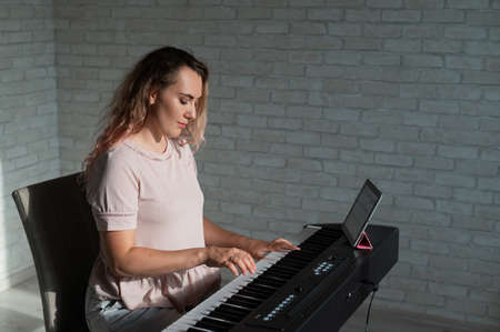 Caucasian woman teaches playing the electric piano online on a digital tablet