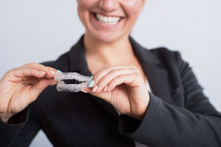 Smiling business woman holding two transparent aligners