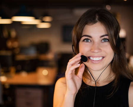 Portrait of a beautiful smiling woman call center operator with a headset at the desk