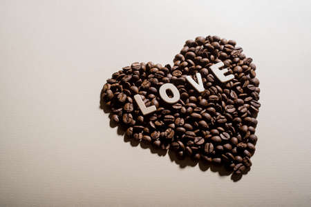 Coffee beans in the shape of a heart and the inscription love on a backgroundの写真素材