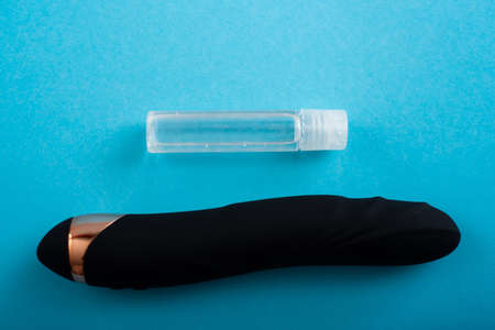 Top view of a black dildo and a bottle of lubricant on a blue backgroundの写真素材