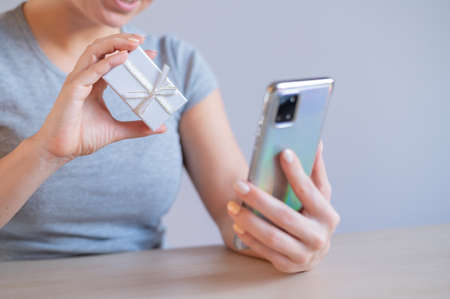 Faceless woman demonstrates gift box over online video link. Online store of gift wrapping for jewelryの写真素材