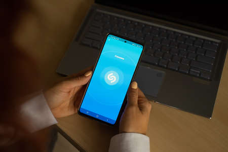 October 18, 2020 Russia, Novosibirsk: A woman uses the Shazam music recognition application on her...