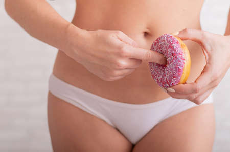 A faceless woman in white panties holds a pink donut imitating sex. A hint of a gesture of sexual intercourseの写真素材