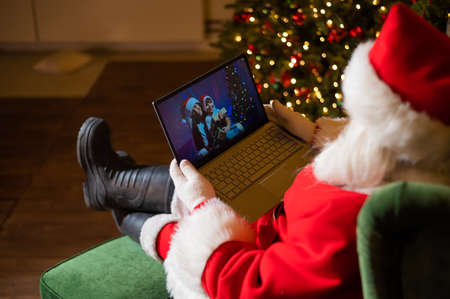 Happy mom and son talking to santa claus by video chat on a laptop. Woman and boy remotely wishes Merry Christmasの写真素材