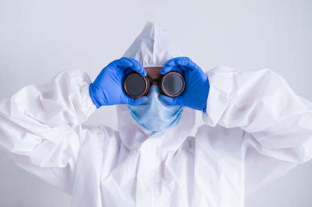 Woman doctor in a protective suit holds on to glassesの写真素材