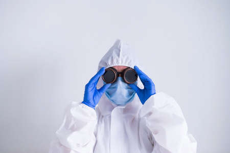 Woman doctor in a protective suit holds on to glassesの写真素材