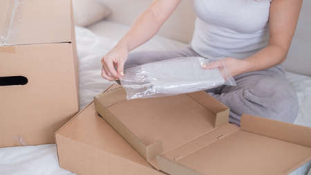 Caucasian woman opens an order while sitting in bed. Online shopping concept with home deliveryの写真素材