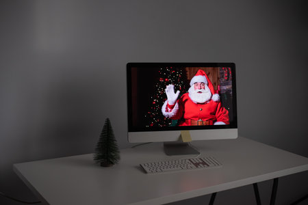 Santa Claus remotely wishes Merry Christmas via a video call on the computer. A man dressed as Santa...