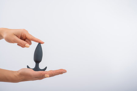 Faceless woman holding a black anal plug on a white background. Assortment of sex shopの写真素材