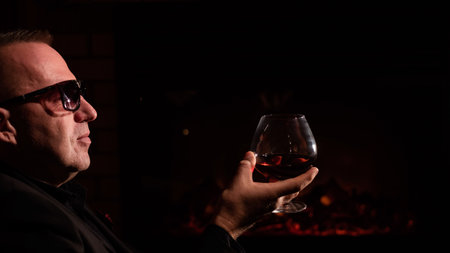 Mature man drinking cognac by the fireplace.の写真素材