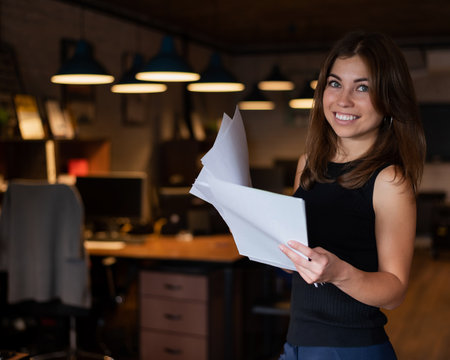 Beautiful young woman holding documents while standing in office.の写真素材