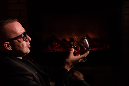 Mature man drinking cognac by the fireplace.の写真素材