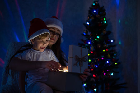 Exciting Mom and son open a glowing gift box at a magical Christmas night