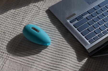 Clitoral vibrator and laptop on the bed in a white sheetの写真素材