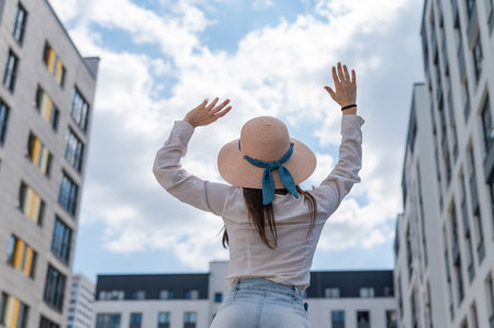 Rear view of a woman in a hat sitting on the background of the cityの写真素材