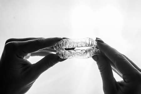 Transparent trays for correcting teeth in female hands. Removable plastic retainersの写真素材