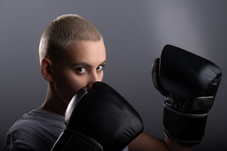 Young woman with short hair in boxing gloves on a white background