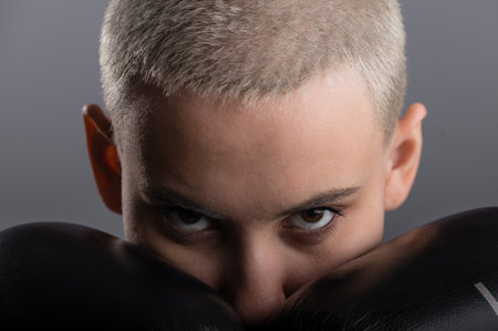 Young woman with short hair in boxing gloves on a white background